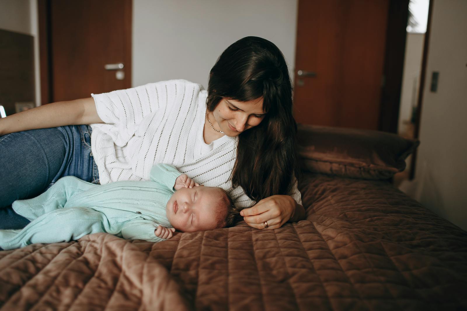 Mother resting beside her sleeping newborn
