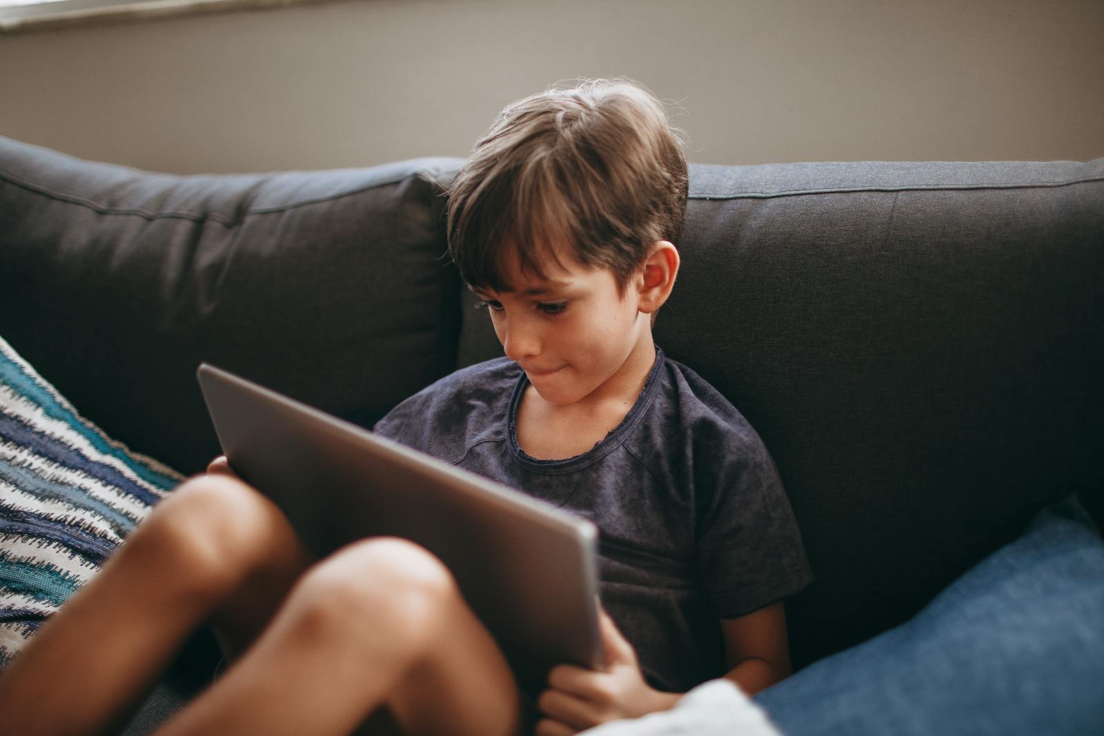 Child using a tablet on the sofa