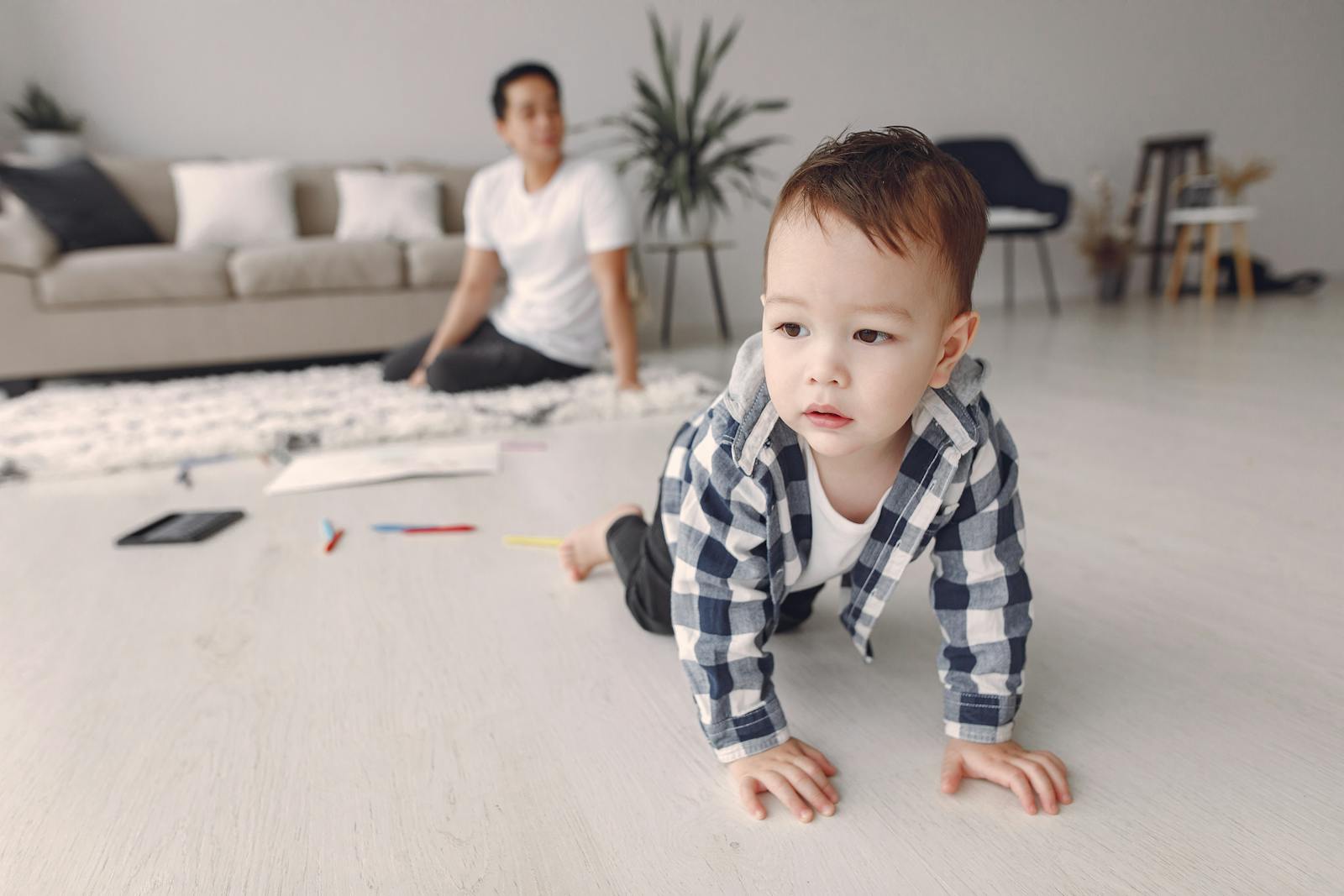Baby crawling on the floor while a parent watches