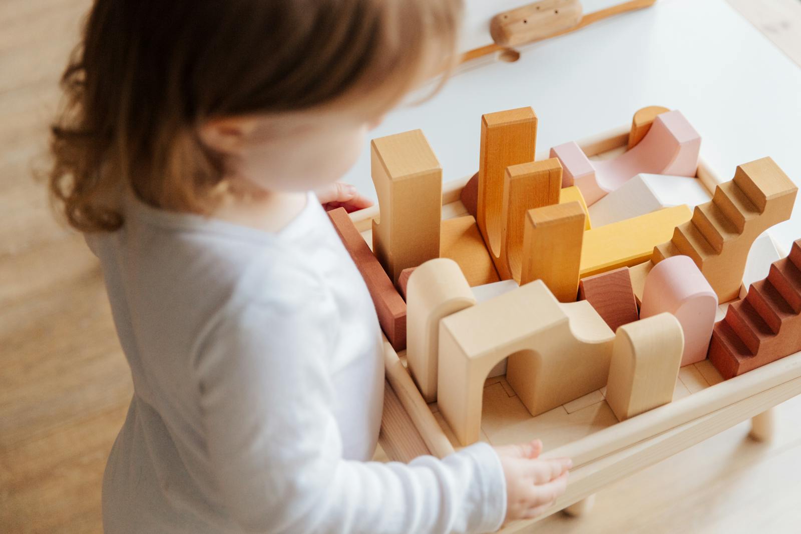 Little girl playing calmly with wooden blocks