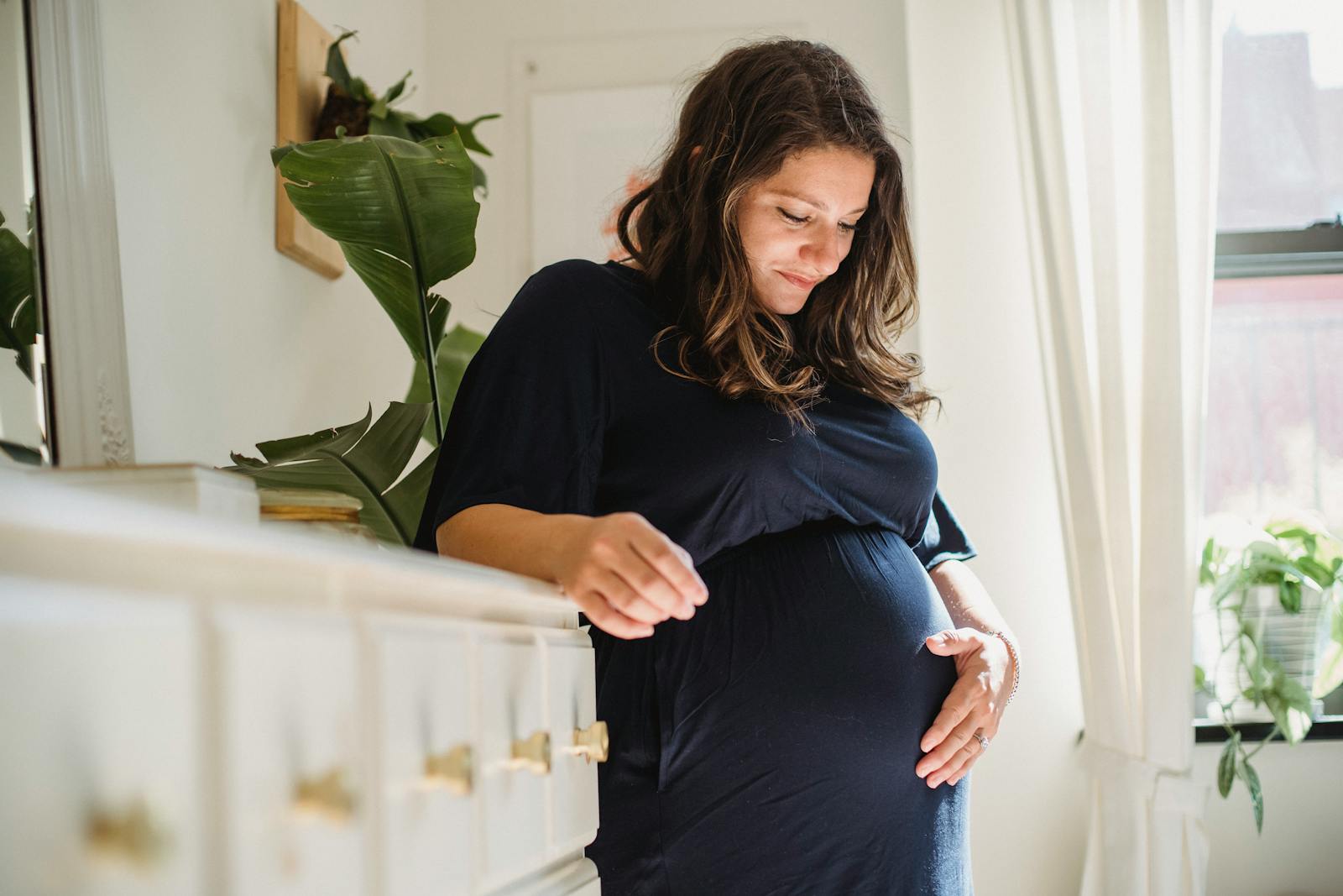 Pregnant woman cradling her belly in a sunlit room