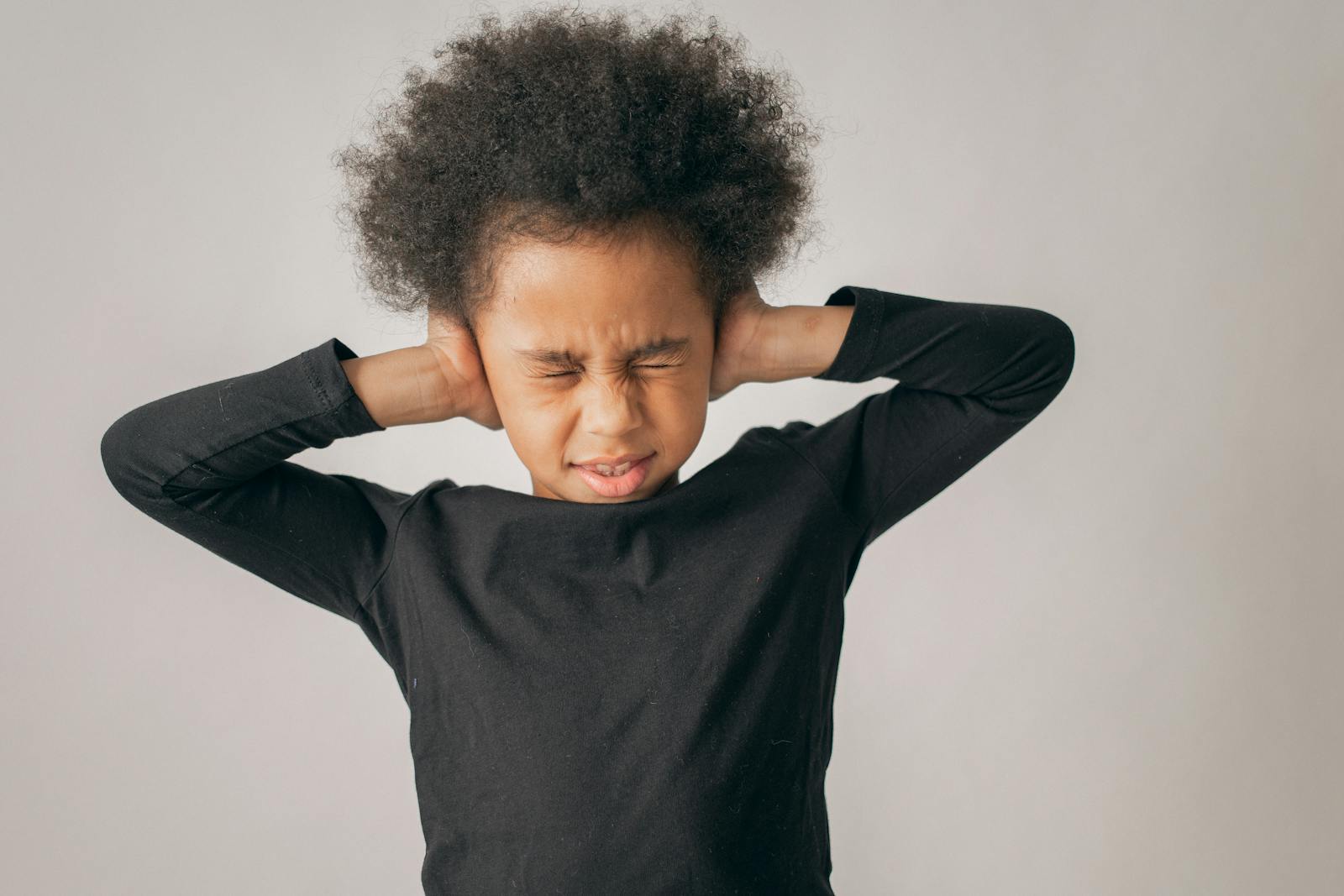 Young child covering ears with eyes closed